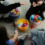 a group of children sitting around a bucket of candy