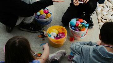 a group of children sitting around a bucket of candy
