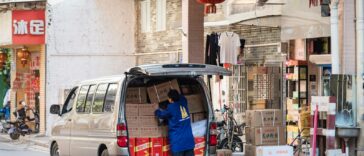 man in blue shirt and blue denim jeans standing beside white van