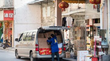 man in blue shirt and blue denim jeans standing beside white van