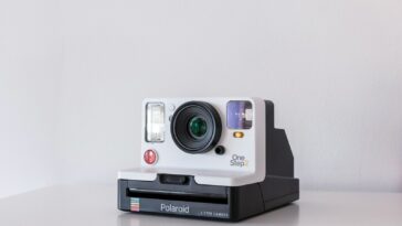 white and black Polaroid One Step 2 instant camera on white board