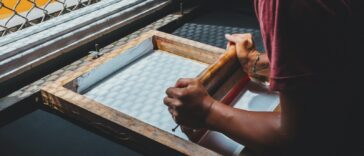 man holding printing screen near white window