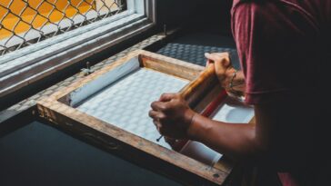 man holding printing screen near white window